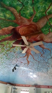 A tree is painted on the ceiling with the viewer's perspective directly beneath a cross-section of the trunk, and branches and leaves radiating in all directions.